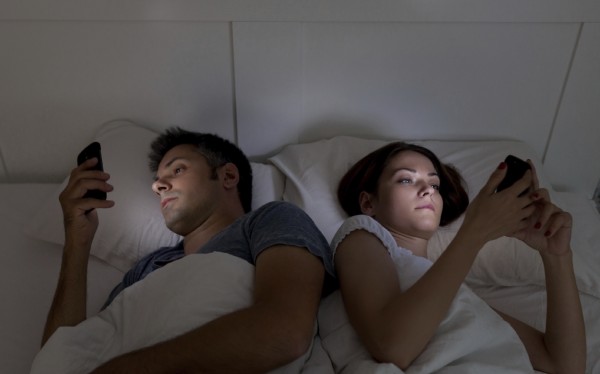 Young couple with smartphones in their bed